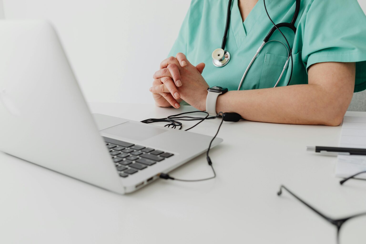 Medical professional in scrubs using a laptop for a remote telemedicine consultation, representing virtual healthcare support and hospital telemedicine services.